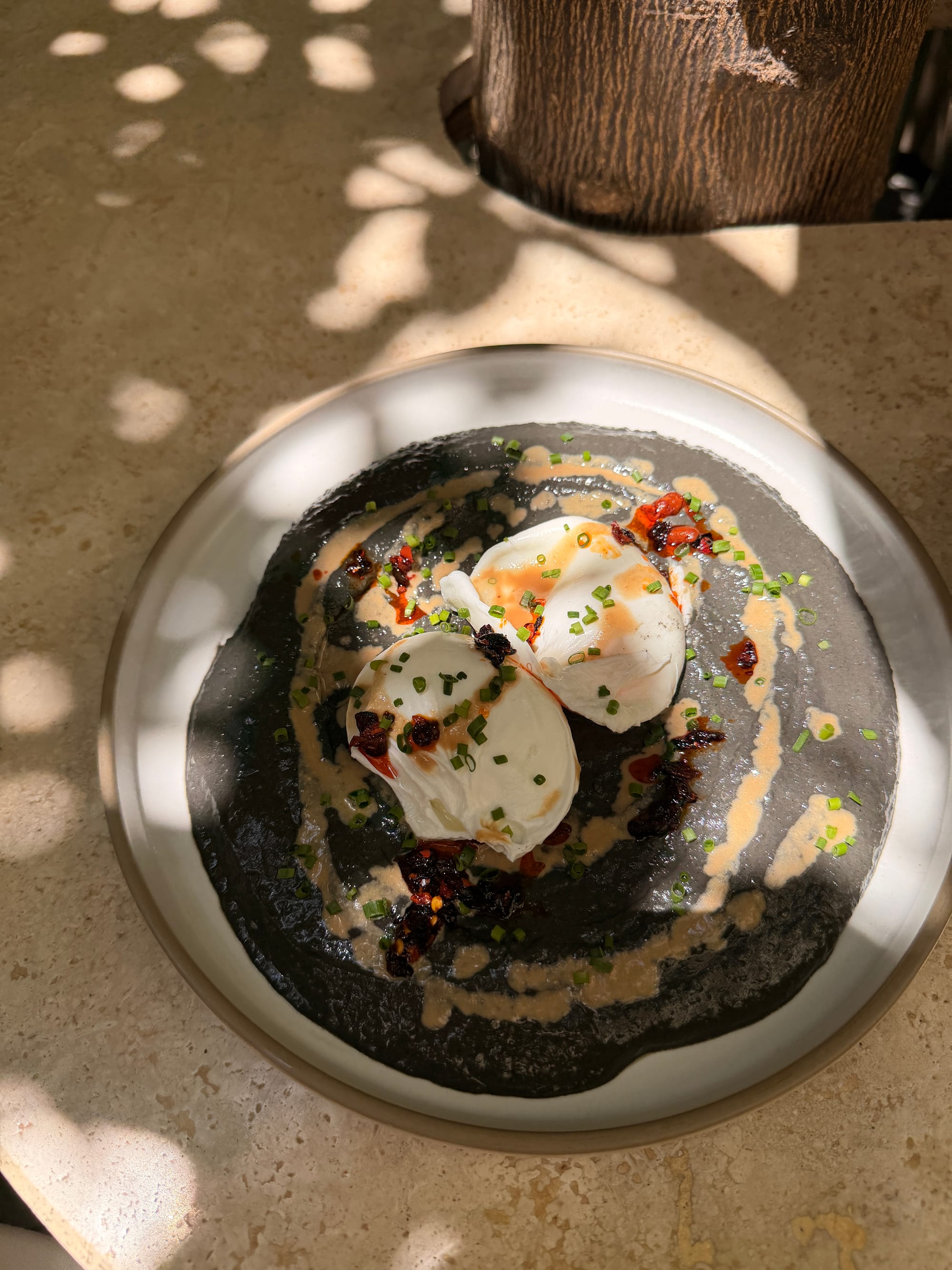 Poached eggs on black sesame hummus with chili crunch and chives
