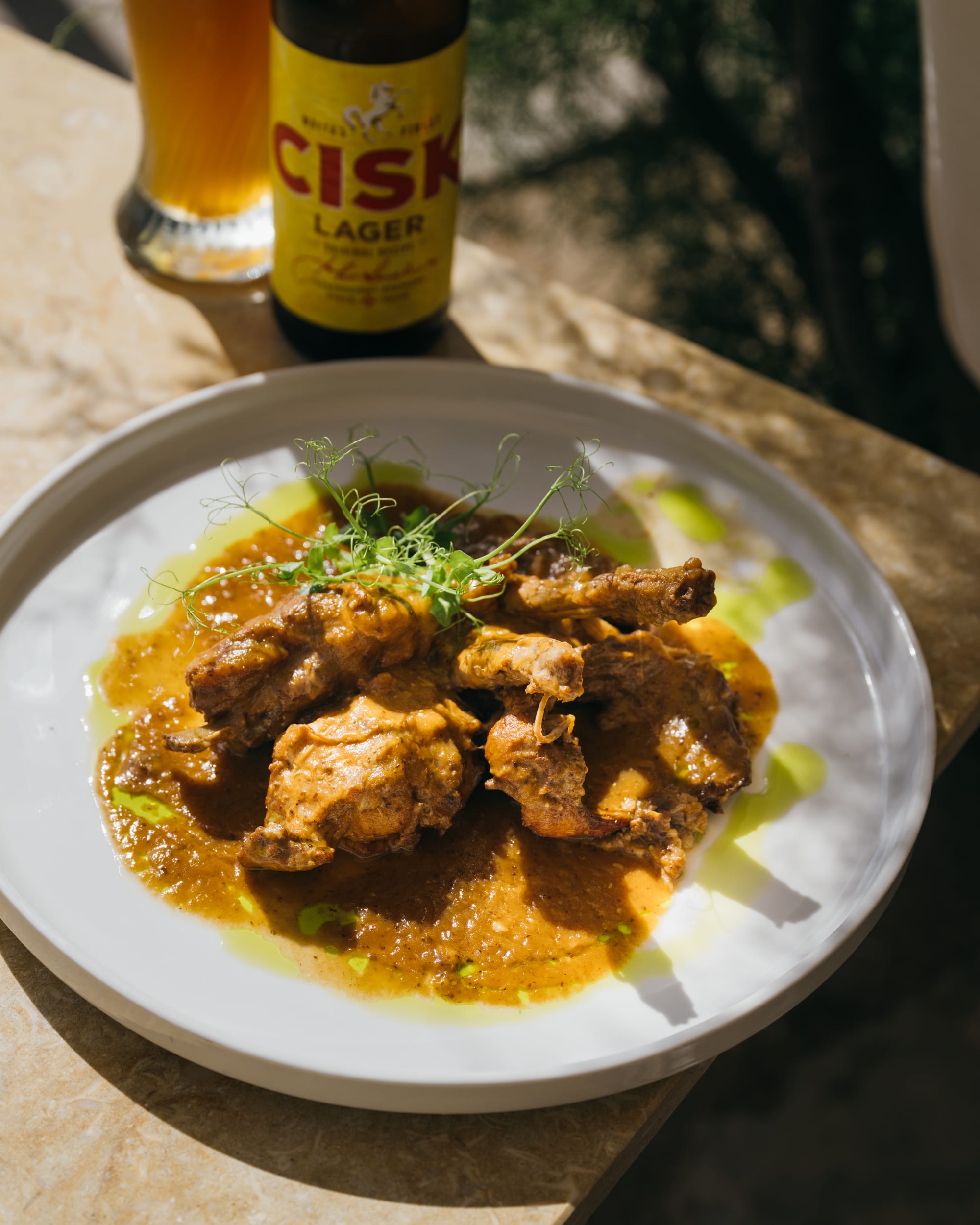 A slow-cooked stew with a cold Cisk lager